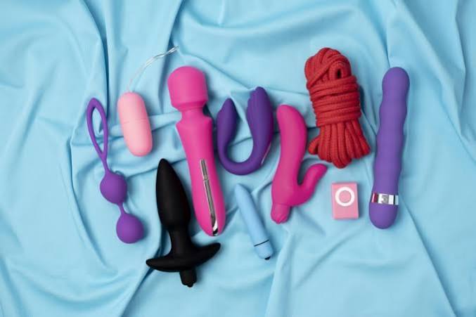 Personal massagers and shaped toys arranged on a pale blue cloth